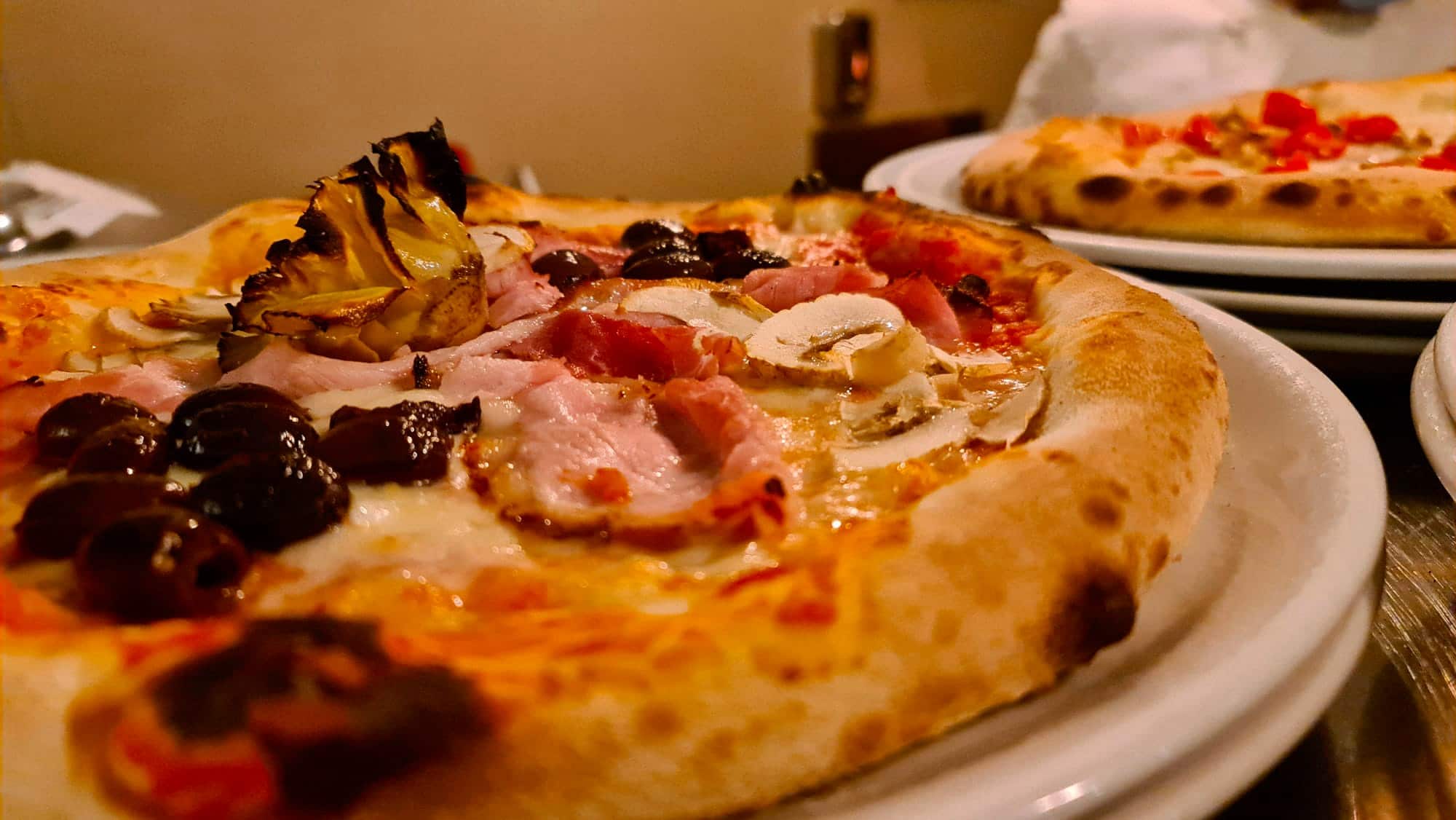 Pizza gourmet con prosciutto, olive taggiasche, funghi e carciofi