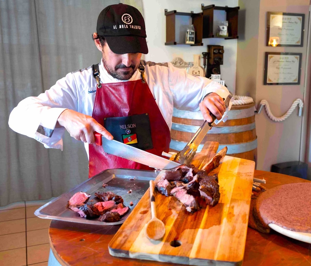 Chef Al Molo Tredici affetta una bistecca di carne alla brace su tagliere di legno
