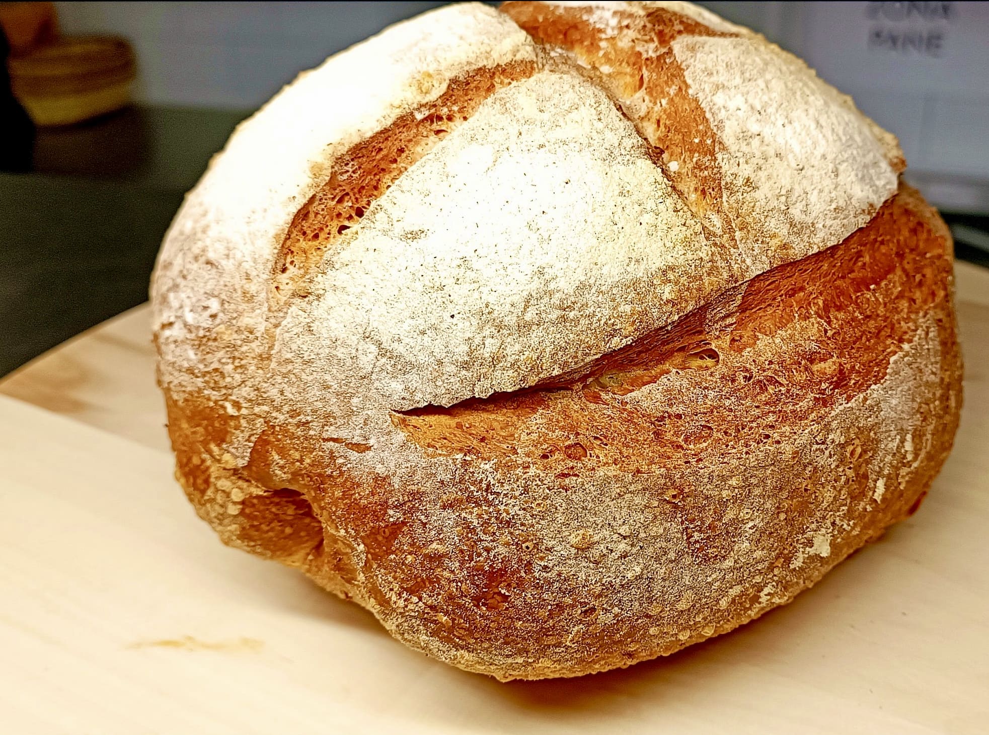 Pagnotta di pane fatto in casa appena sfornata, crosta dorata e infarinata