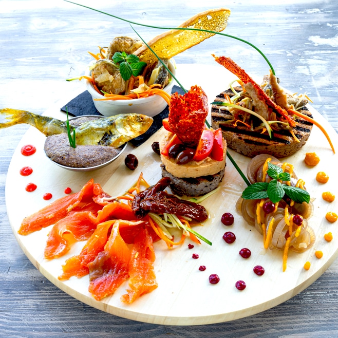 Tagliere tondo con selezione di pesce: salmone marinato, tartare, pesce grigliato e crostini