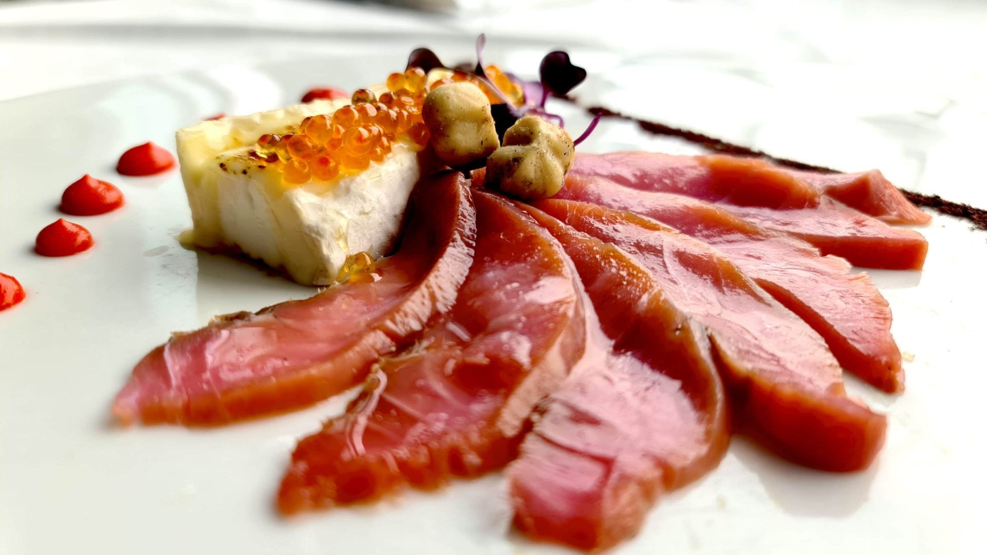 Piatto gourmet con carpaccio, robiola, uova di salmone e nocciole