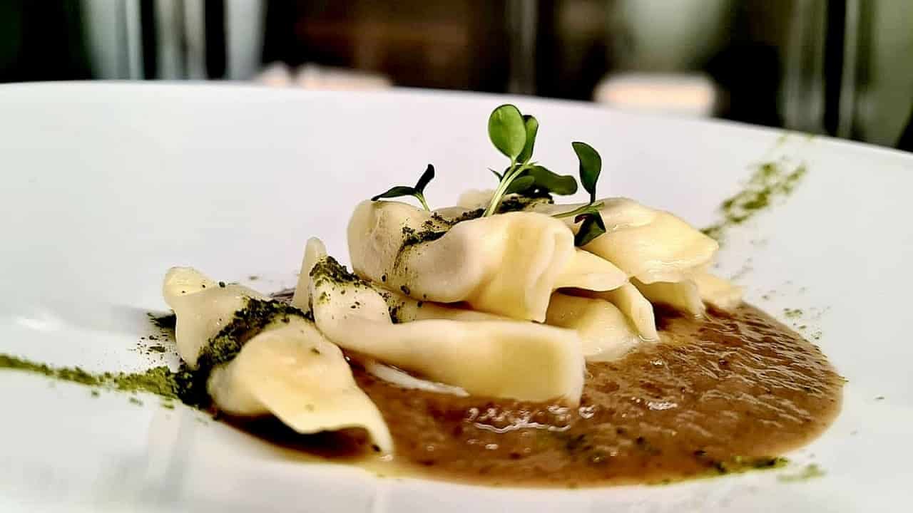 Piatto di pasta fresca ripiena con salsa e polvere di erbe — cucina del ristorante Al Molo